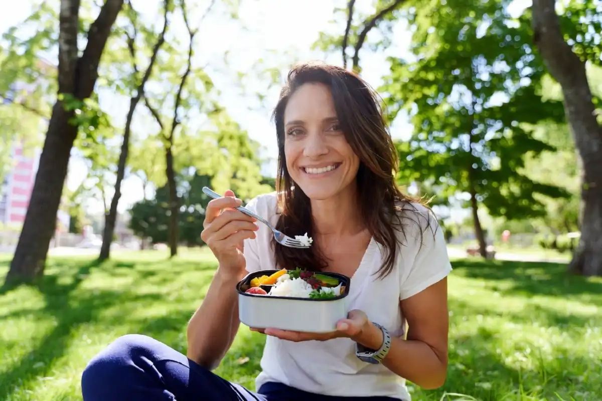 Person enjoying lunch outdoors surrounded by nature for productivity reset