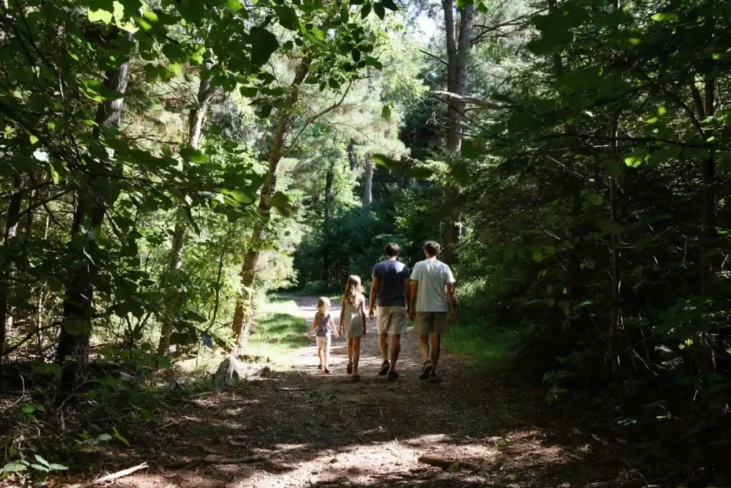 Family hiking on a shaded forest trail at Indian Creek Nature Center in summer