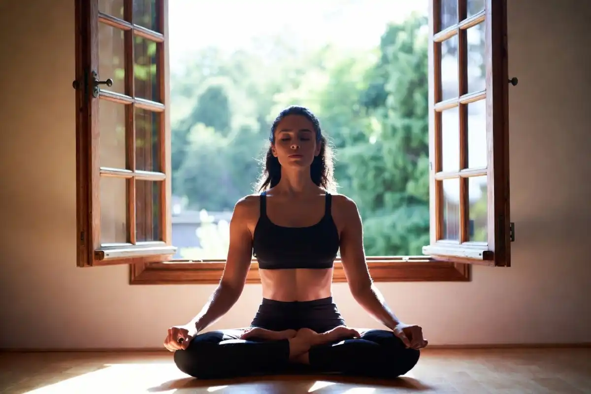 Person meditating in morning daylight by an open window