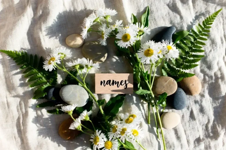 Wildflowers, ferns, and smooth stones arranged on linen to represent nature girl names inspiration