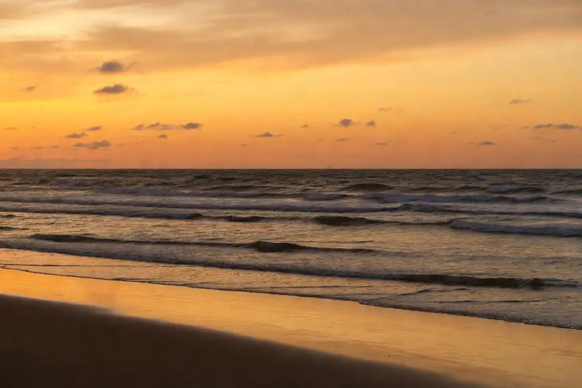Ocean waves rolling gently onto a sandy shore at sunset