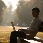 Person working on laptop outdoors with morning sunlight for productivity nature boost