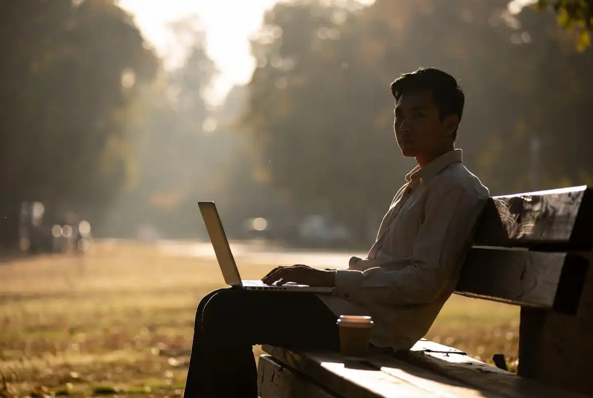 Person working on laptop outdoors with morning sunlight for productivity nature boost