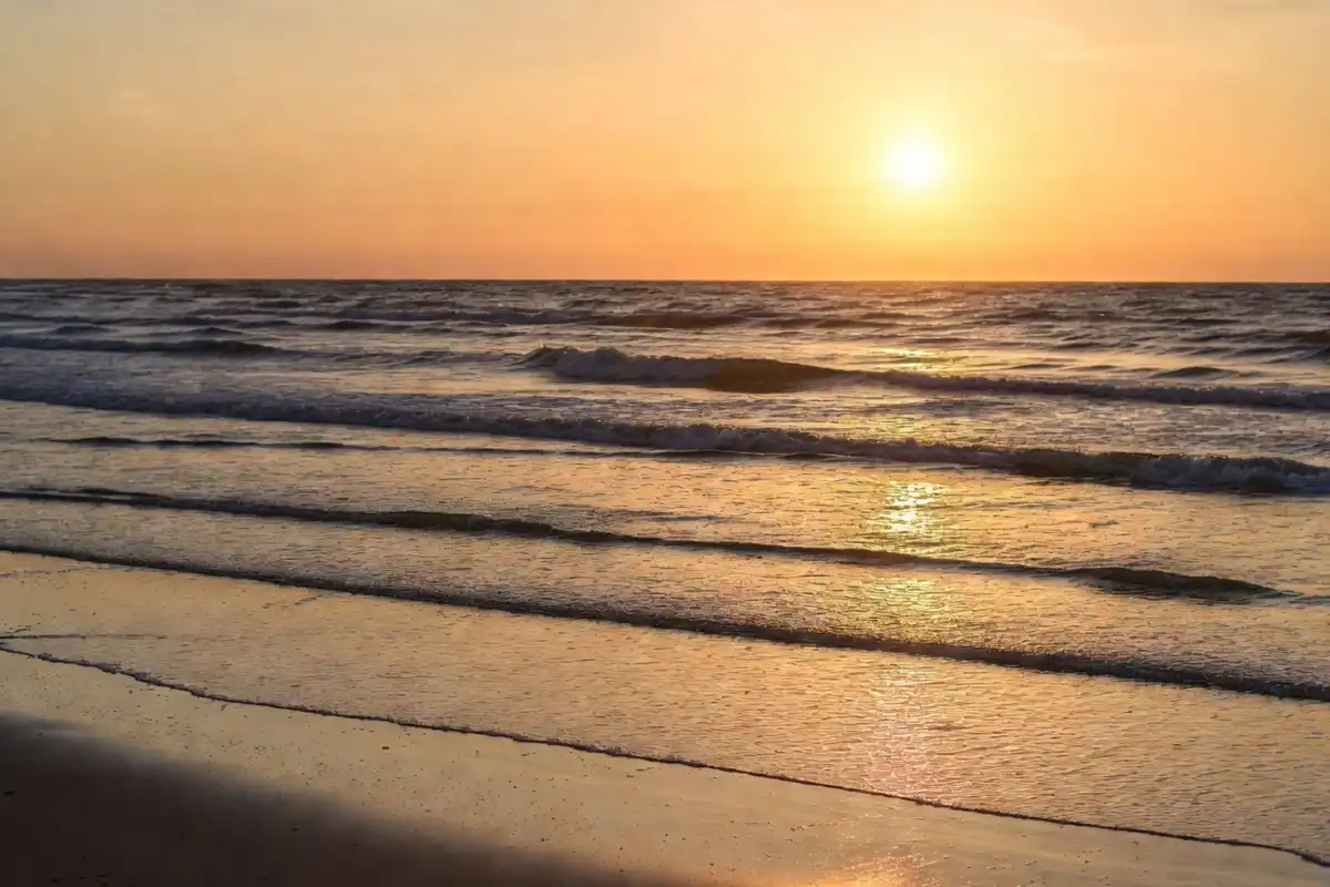 Gentle ocean waves on a sandy shore at golden hour complementing quotes about nature and water