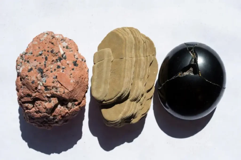 Three types of natural stone samples including granite, sandstone, and obsidian on a white surface