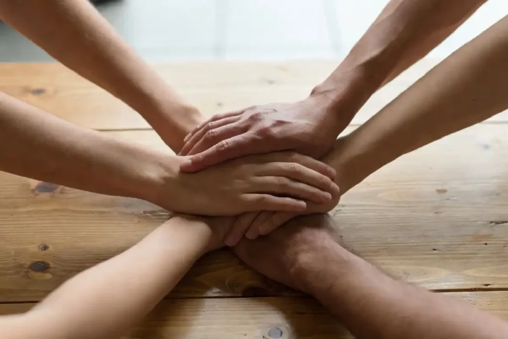 Four diverse hands joined together on a table symbolizing collaboration and teamwork