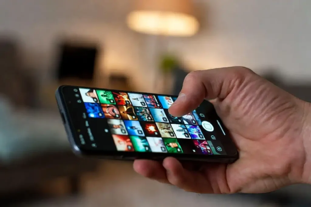 A hand holding a phone showing a gallery of saved RedGif videos on screen
